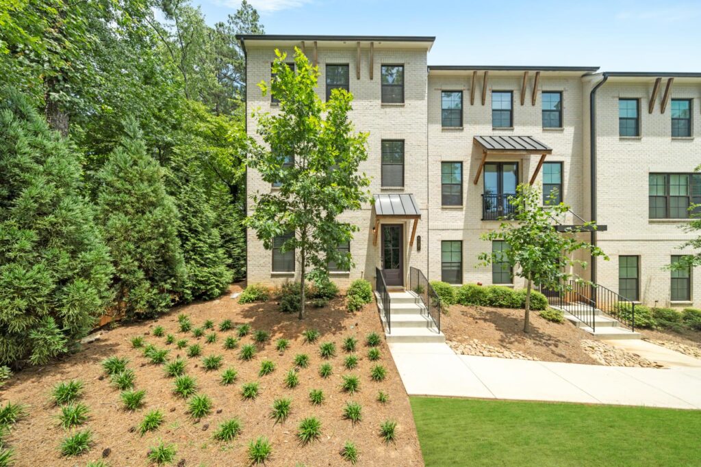 Townhome exterior with light brick, black-framed windows, and landscaped front yard.