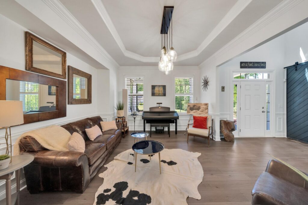Stylish living room with coffered ceiling, leather sofa, and decorative mirrors.