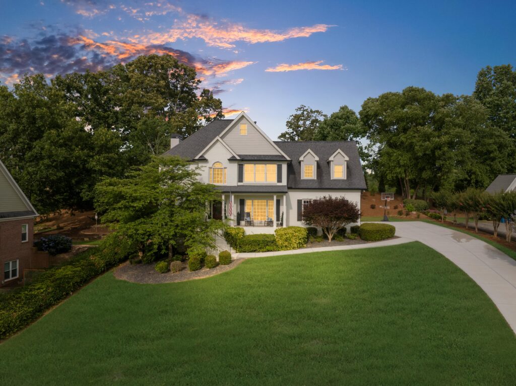 Two-story suburban home with a large front lawn and a dramatic sunset sky.