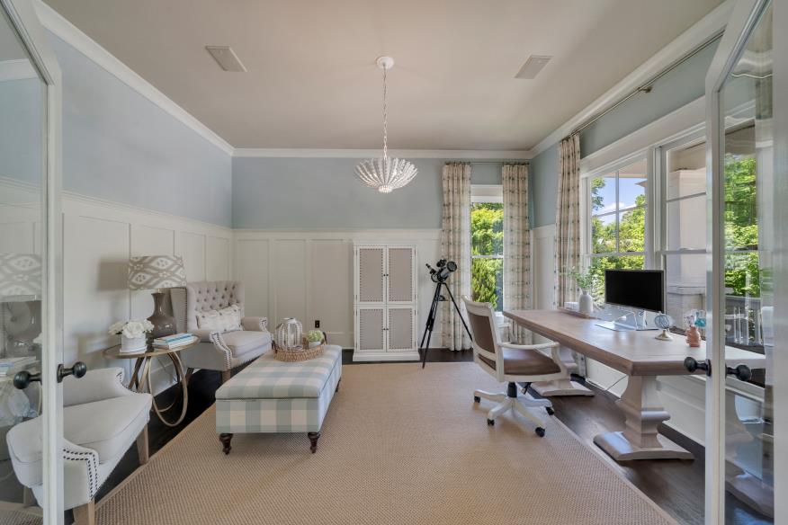 Elegant home office with a desk, plush seating, and large windows letting in natural light.