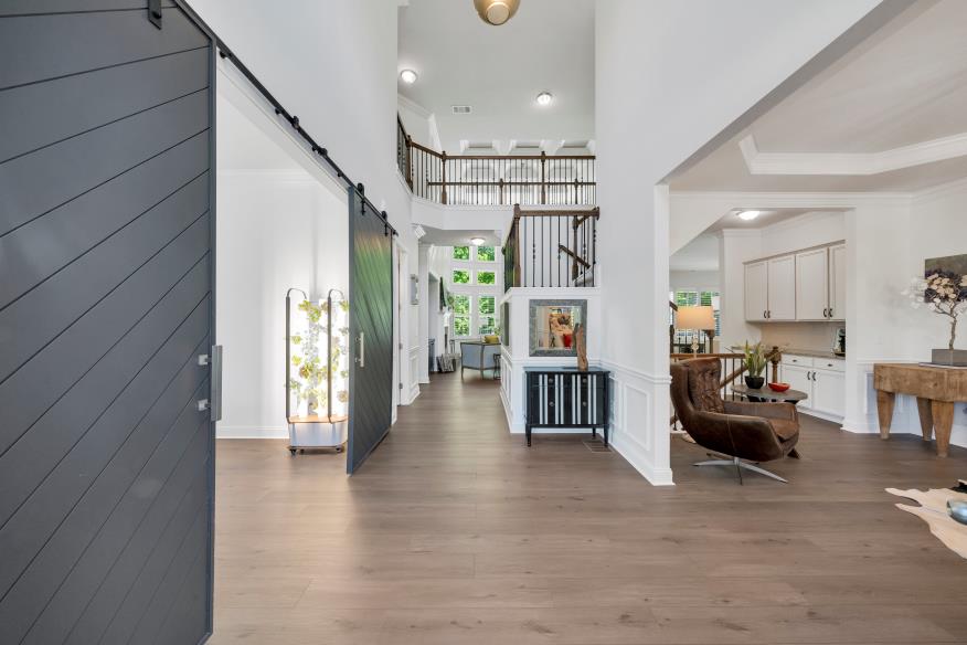 Spacious home entry with modern barn doors, staircase, and open layout featuring bright natural light.